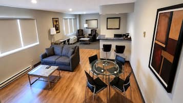 Una sala moderna con sofá, mesa de centro y una mesa de comedor con cubierta de vidrio y sillas.