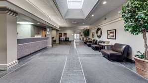 Un vestíbulo de hotel con mostrador de recepción, zona de estar y una planta grande.