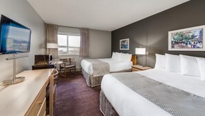 Una habitación de hotel con dos camas, un escritorio, un televisor y una ventana con cortinas.