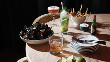 Una mesa de comedor con diversos platos, incluyendo mariscos, un cóctel y una botella de vino.
