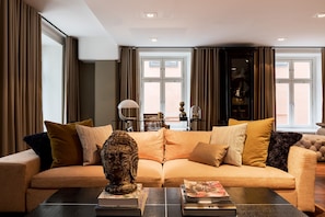 Ett modernt vardagsrum med en beige soffa, ett soffbord och en dekorativ skulptur.