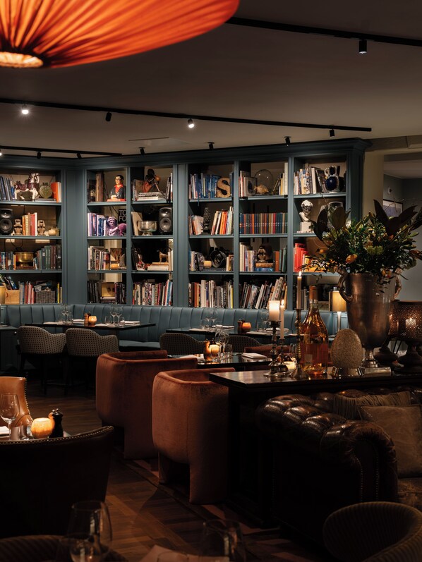 A cozy library with bookshelves, seating, and a dining area. - Lydmar Hotel (Stockholm)