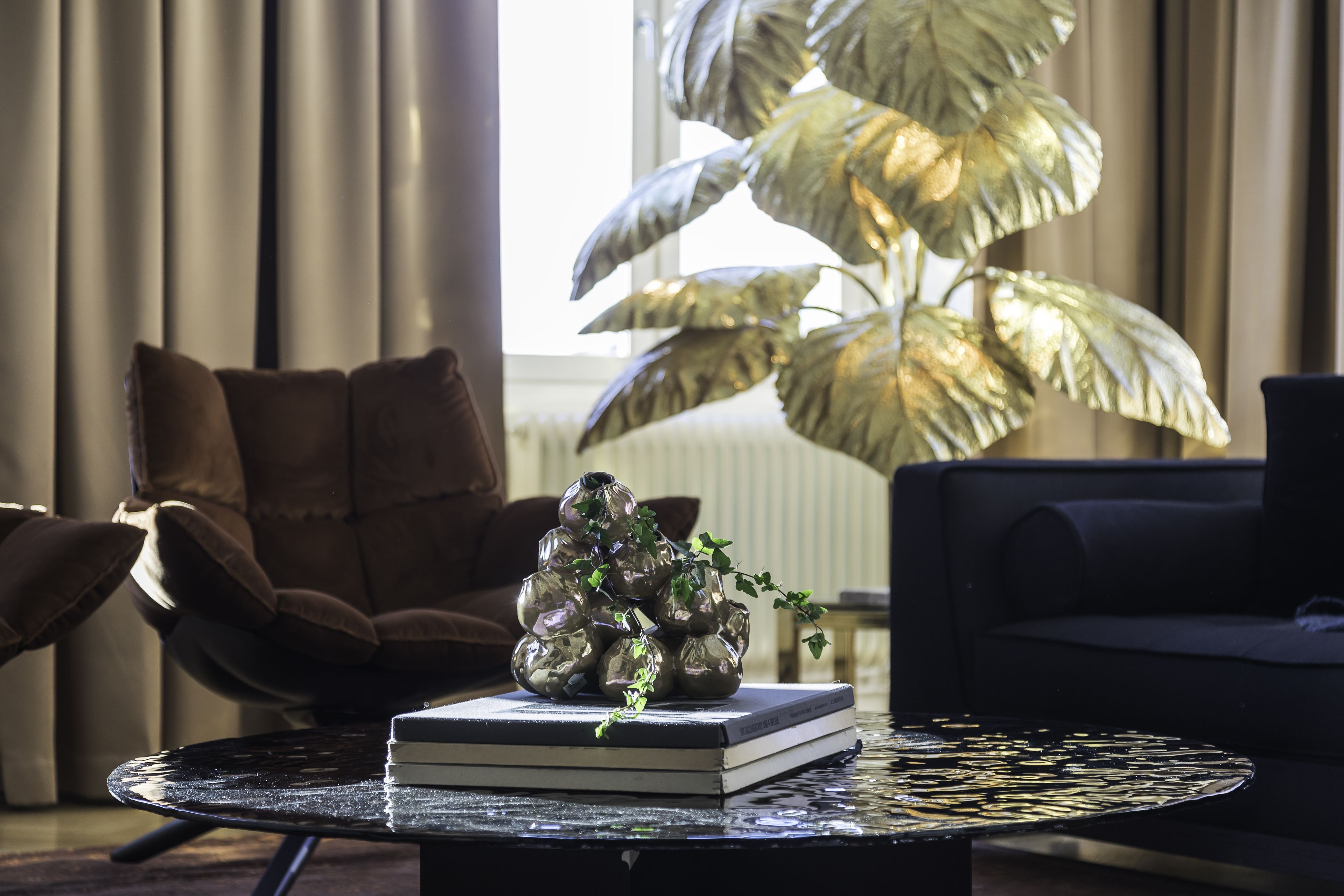 Una sala de estar moderna con una mesa de centro redonda, un sofá y una gran planta en maceta.