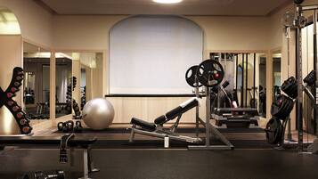 A gym with exercise equipment, a large mirror, and a whiteboard on the wall.