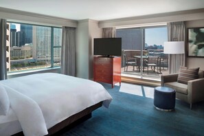 A hotel room with a large bed, a TV, a desk, a chair, a sofa, and a view of the city. - Marriott Downtown at CF Toronto Eaton Centre (Toronto)