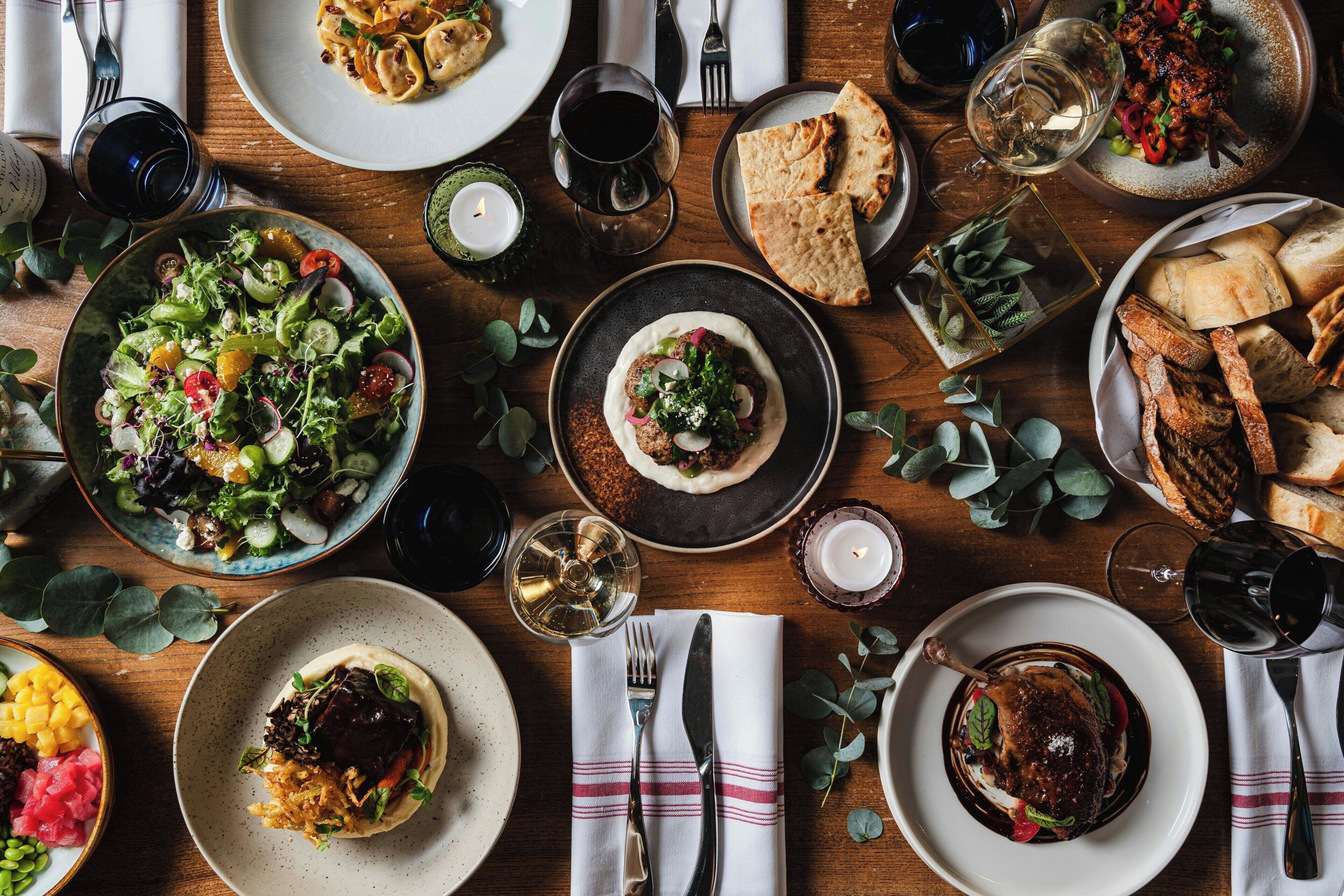 A table set with various dishes, glasses of wine, and bread, suggesting a dining experience.