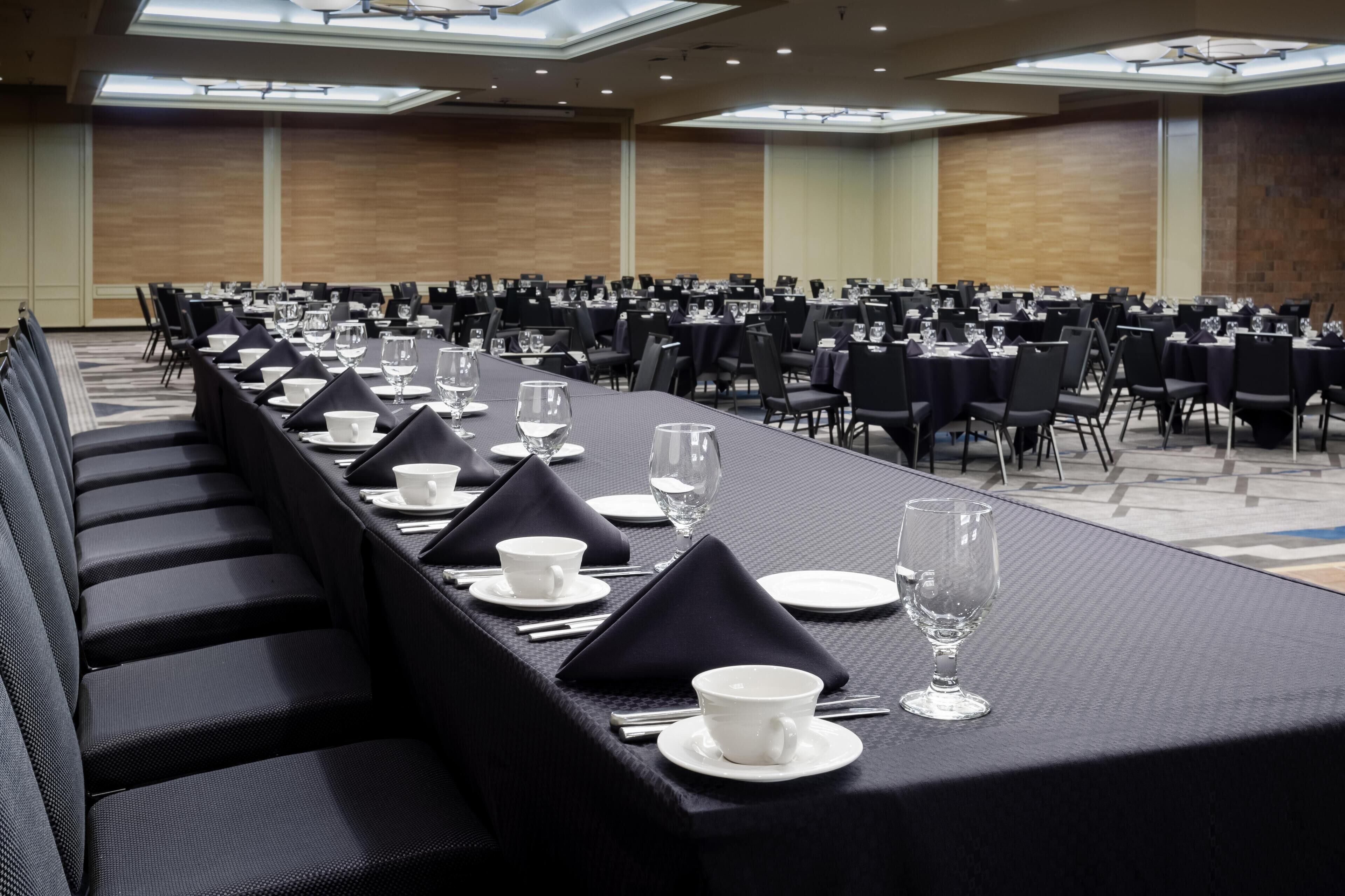 A conference room with rows of tables set for a meeting, equipped with chairs and table settings.