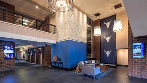 A modern lobby with a high ceiling, a large chandelier, and a seating area with a blue accent wall. - DoubleTree by Hilton Hotel Billings (Billings)