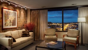 A modern hotel room with a large window offering a city view, a comfortable sofa, two armchairs, and a coffee table. - DoubleTree by Hilton Hotel Billings (Billings)