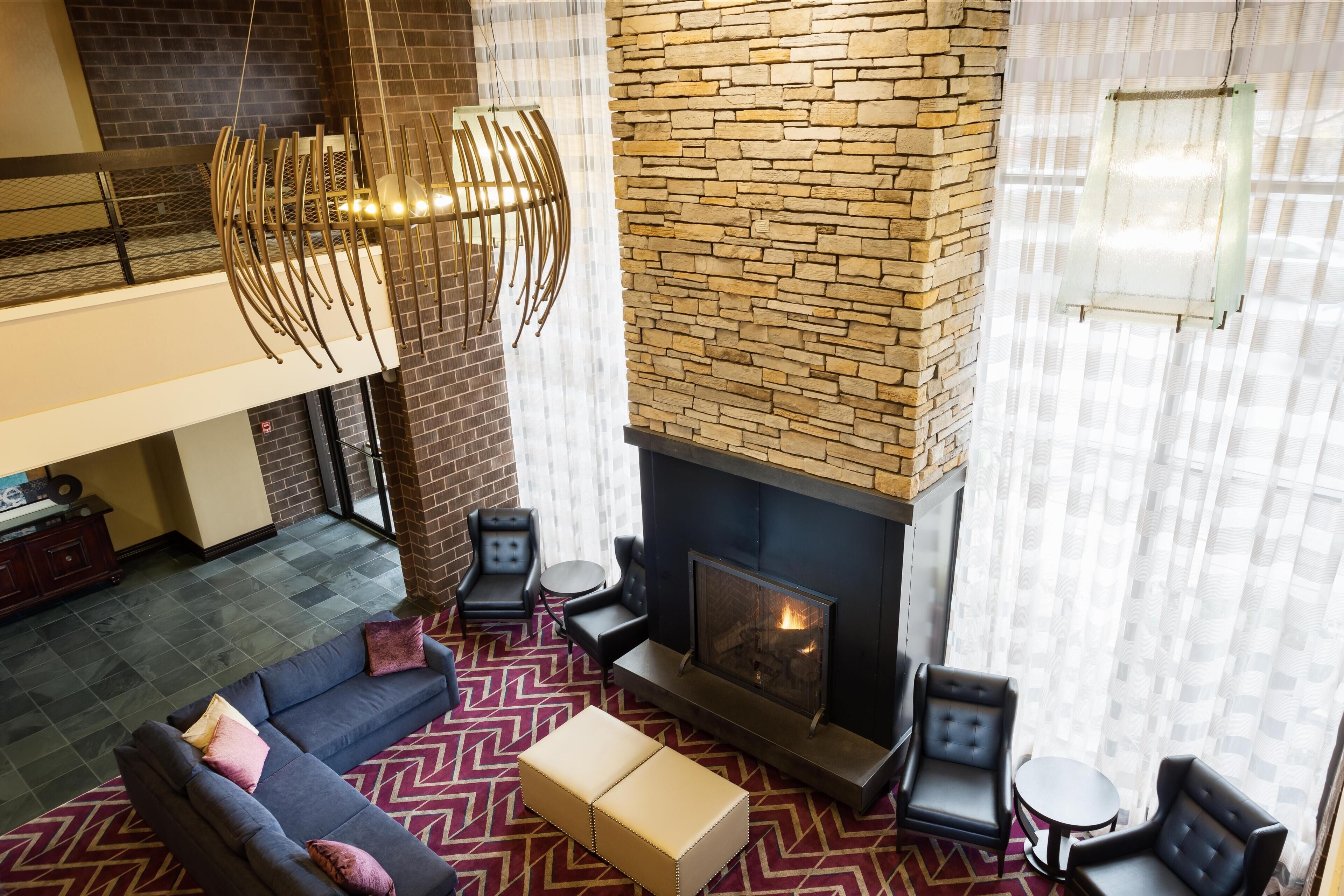 A modern living room with a fireplace, a sofa, a coffee table, and a patterned rug.