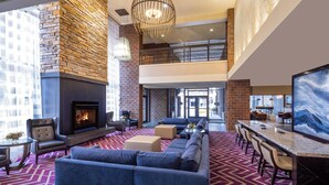 A spacious lobby with a fireplace, seating area, and a high ceiling with a chandelier. - DoubleTree by Hilton Hotel Billings (Billings)