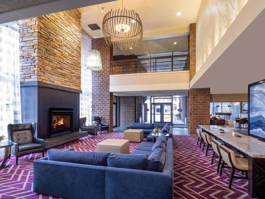 A spacious lobby with a fireplace, seating area, and a high ceiling with a chandelier.