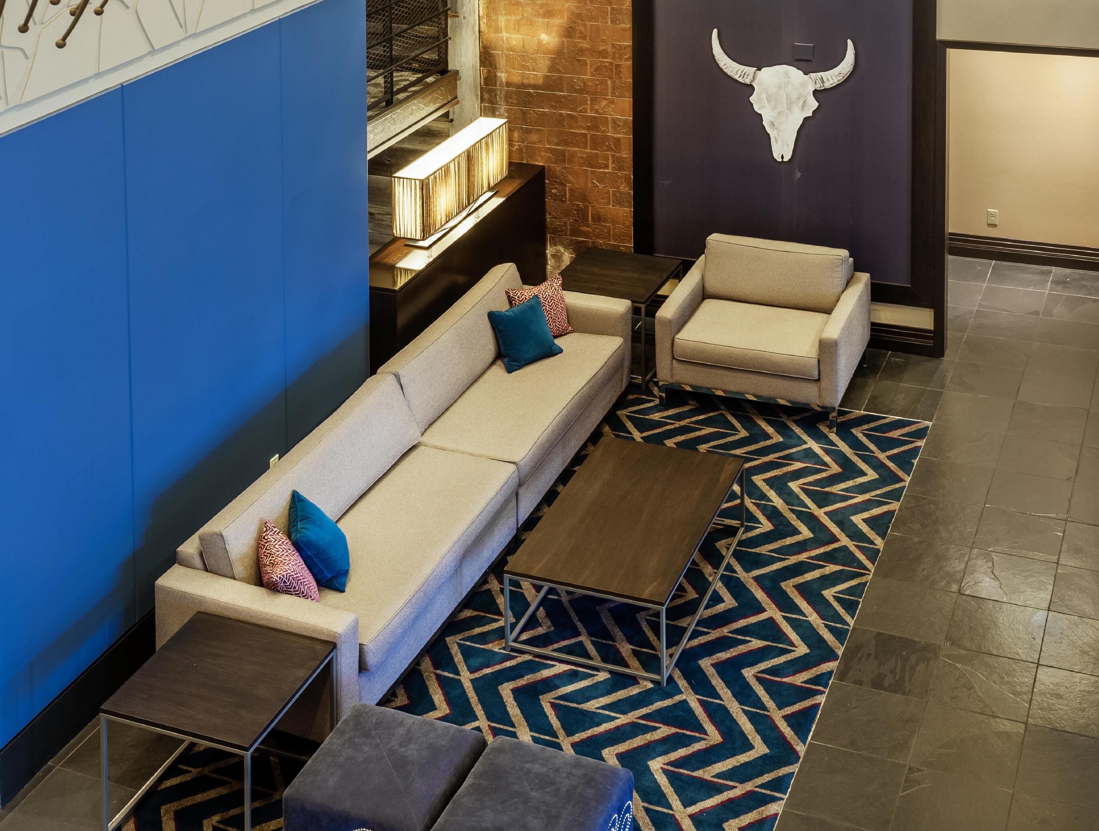 Un área de estar moderna con un sofá, sillones, una mesa de centro y una alfombra estampada.