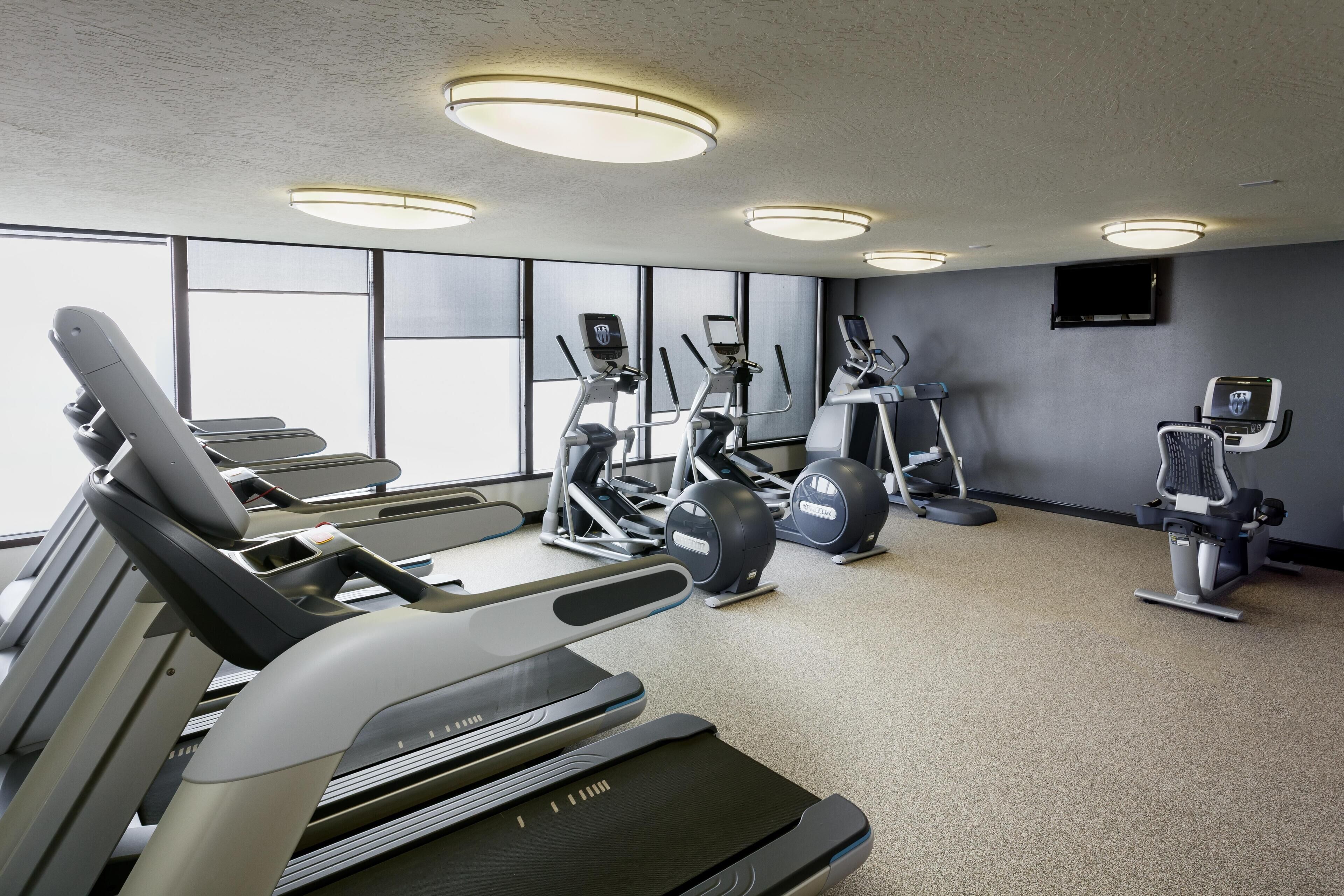 A gym with treadmills, elliptical machines, and weight stations.