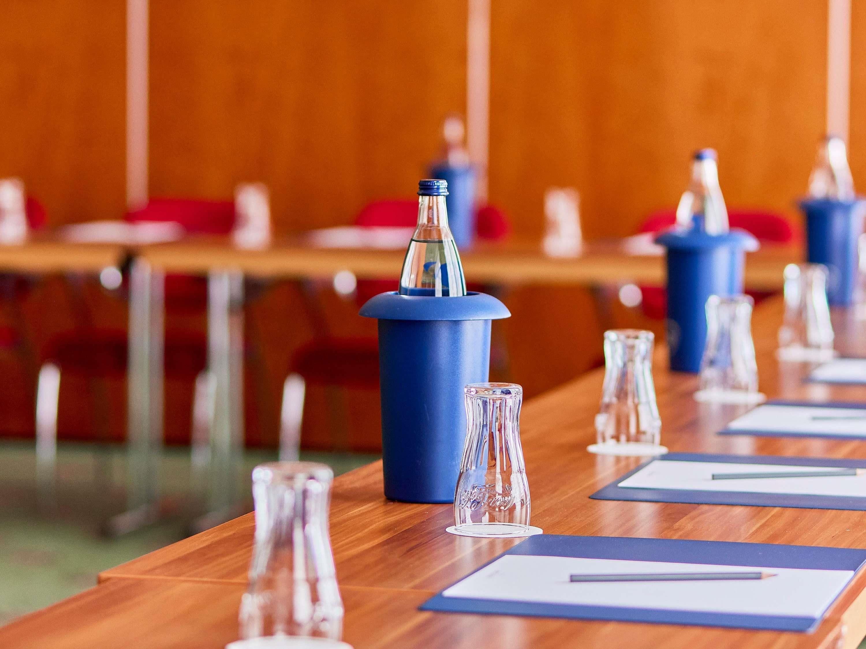 Un salón de conferencias con mesas, sillas y atril azul.