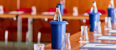 Un salón de conferencias con mesas, sillas y atril azul.
