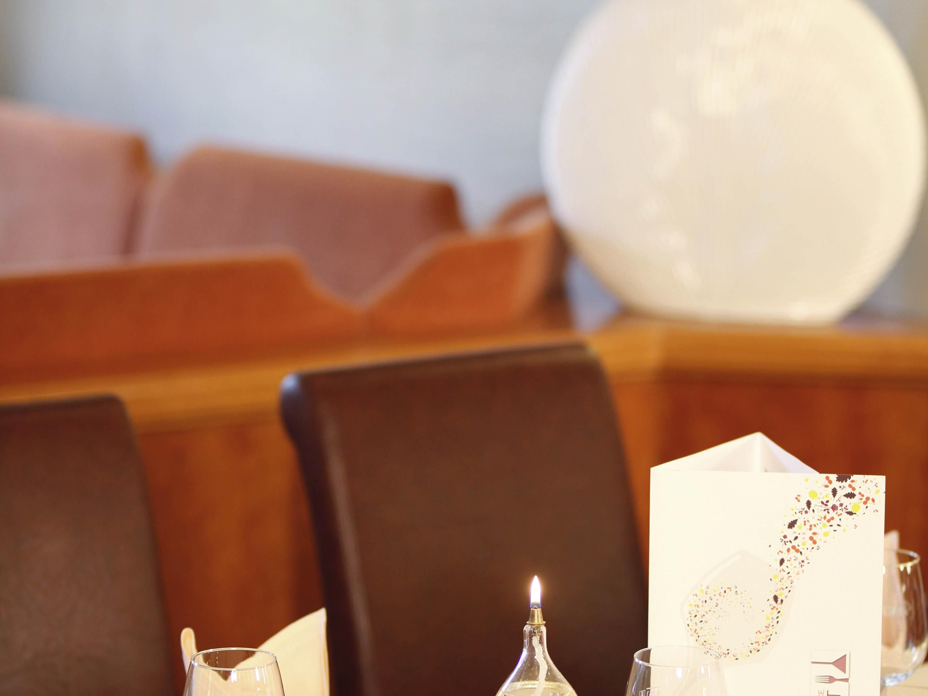 Una mesa de comedor con una vela, un vaso y una servilleta con un diseño decorativo.