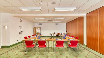 A conference room with a long table, red chairs, and a patterned carpet.