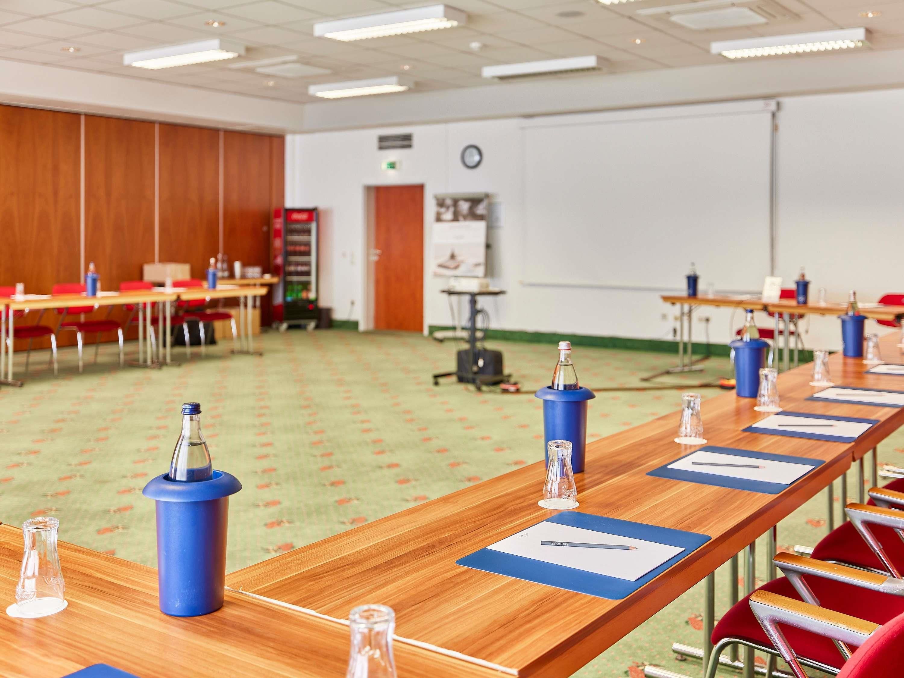 A conference room with long tables, chairs, and blue candle holders.