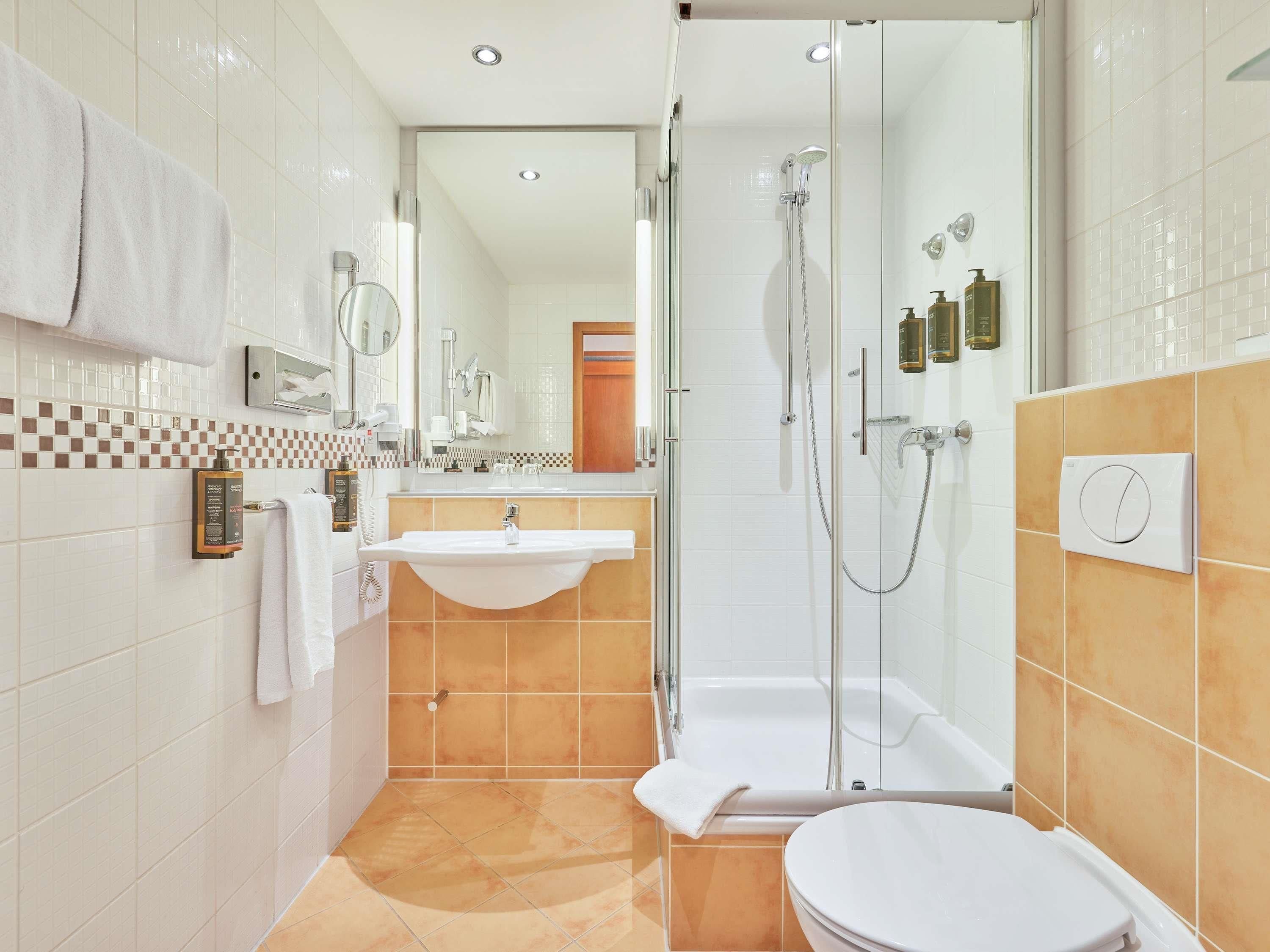 Un baño moderno con ducha de mampara de vidrio, lavabo blanco y retrete.