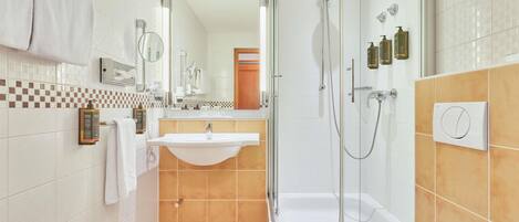 Un baño moderno con ducha de mampara de vidrio, lavabo blanco y retrete.
