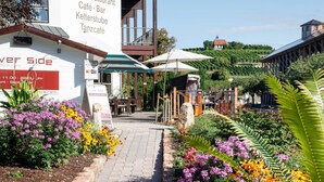 A restaurant with outdoor seating, a signboard, and a garden path. - Mercure Bad Duerkheim an den Salinen (Bad Durkheim)