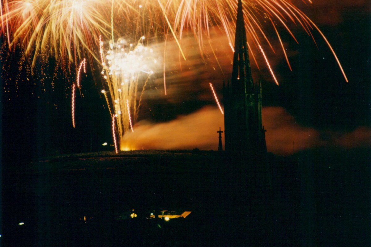 A night scene with fireworks over a city skyline, including a prominent church spire.