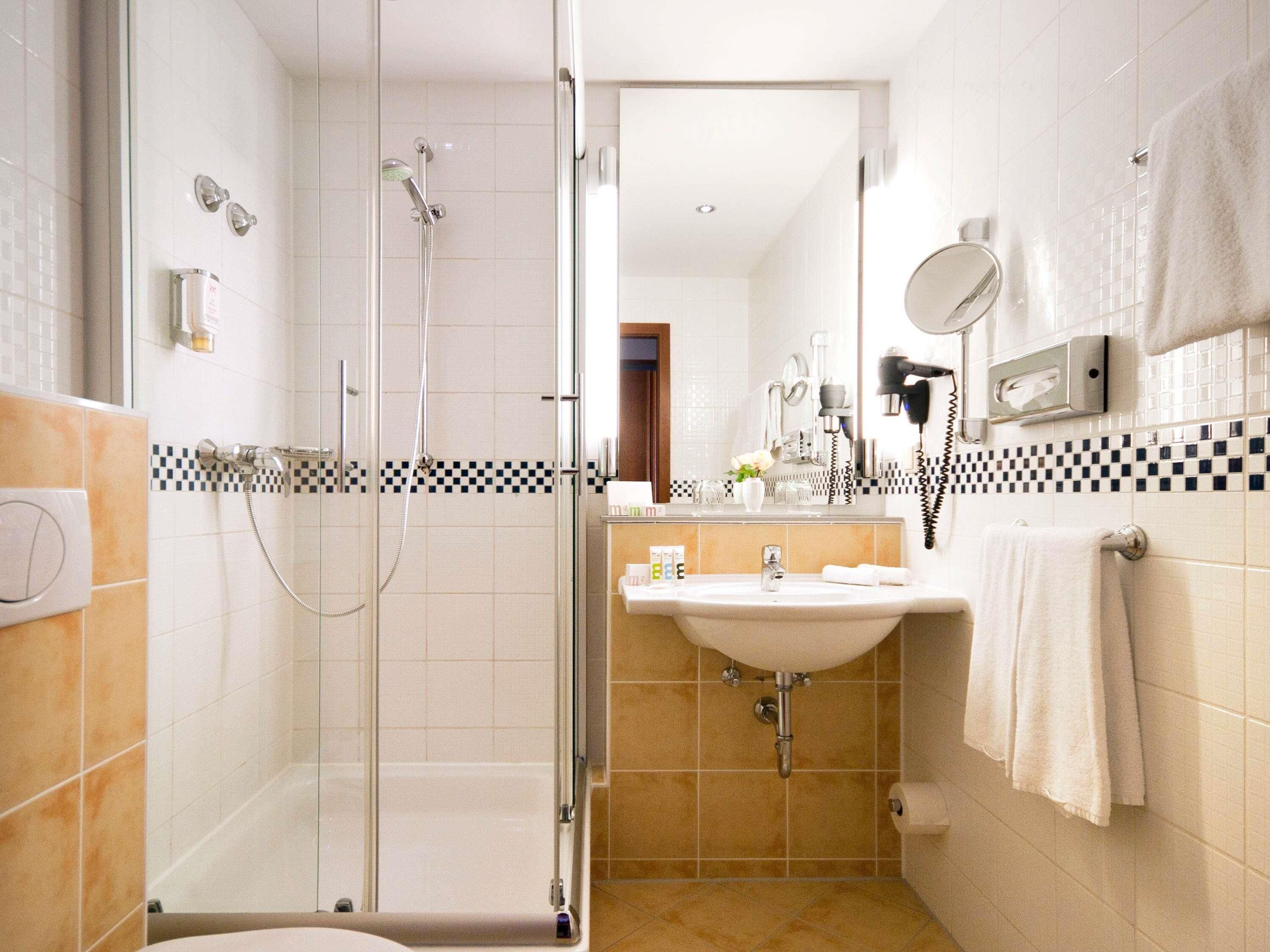 A modern bathroom with a glass-enclosed shower, a sink with a mirror, and a towel rack.