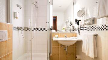 A modern bathroom with a glass-enclosed shower, a sink with a mirror, and a towel rack.