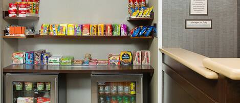 A vending machine with snacks and drinks, a shelf with boxed food items, and a wall sign indicating 'the market'.