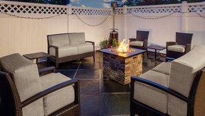 An outdoor patio with wicker furniture, a stone fire table, and a white fence with a lattice top. - Residence Inn by Marriott Cherry Hill Philadelphia (Cherry Hill)