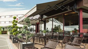 An outdoor seating area with chairs and tables, a building with a red and white facade, and a clear sky.