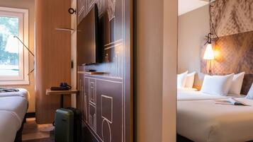 A hotel room with a bed, a desk, a television, and a suitcase.
