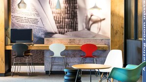 Una sala de reuniones moderna con una mesa larga, cuatro sillas, una mesa redonda y una pared grande con un cartel.