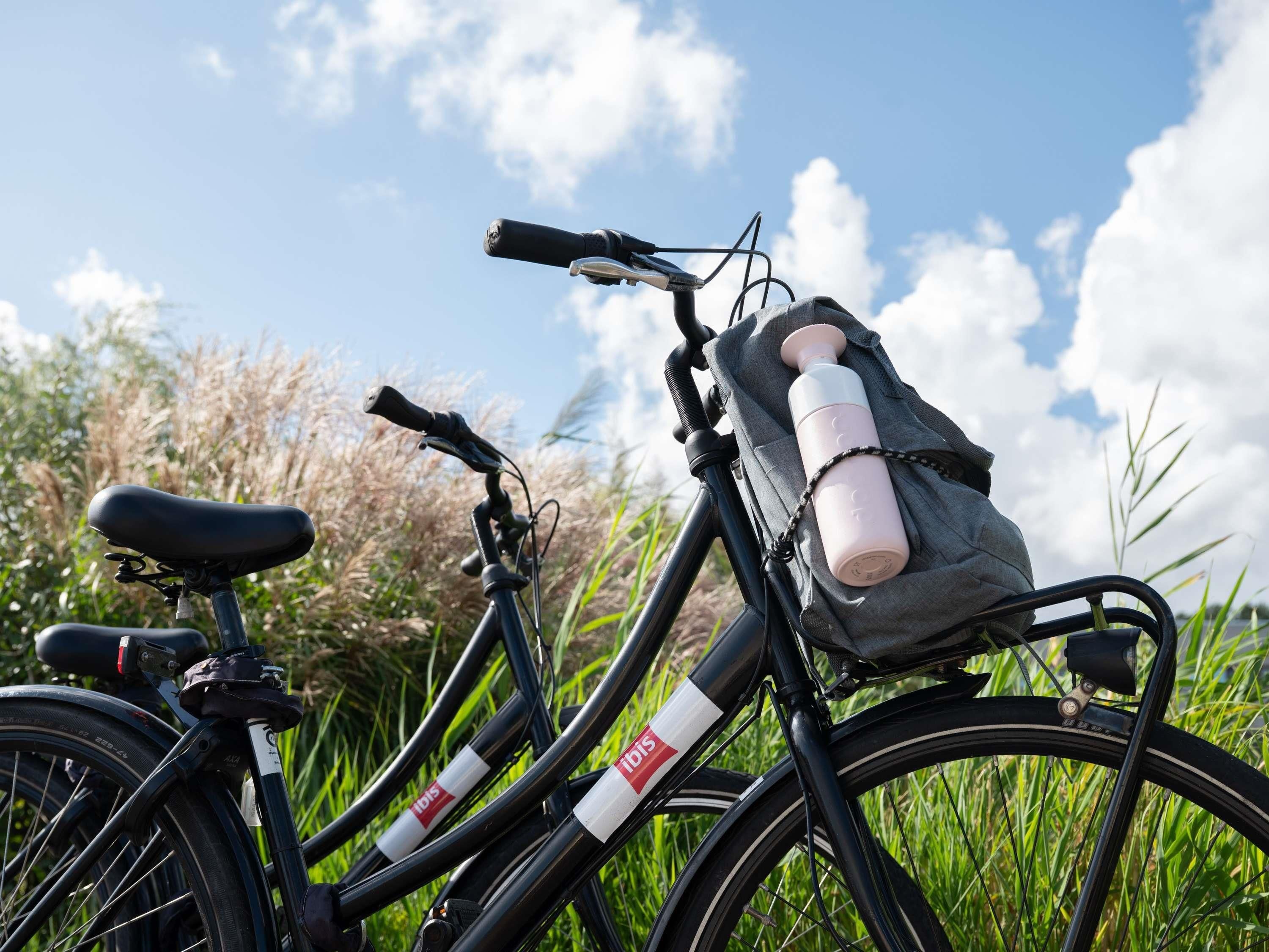 Una bicicleta con una botella de agua y una bolsa sujetas al cuadro, frente a un paisaje natural.