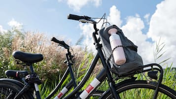 Una bicicleta con una botella de agua y una bolsa sujetas al cuadro, frente a un paisaje natural.