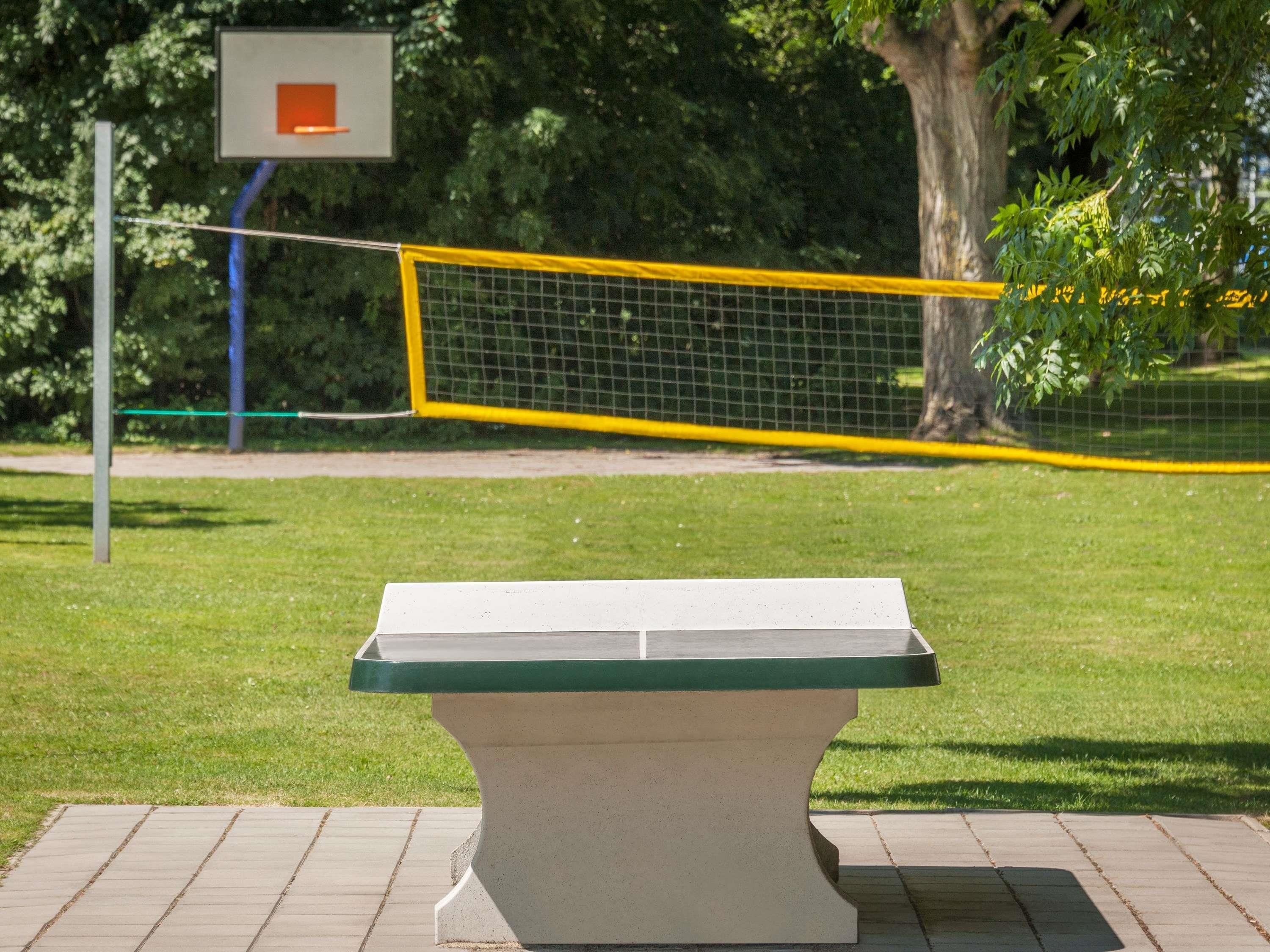 Una cancha de baloncesto con una red, un banco y un cartel en el fondo.