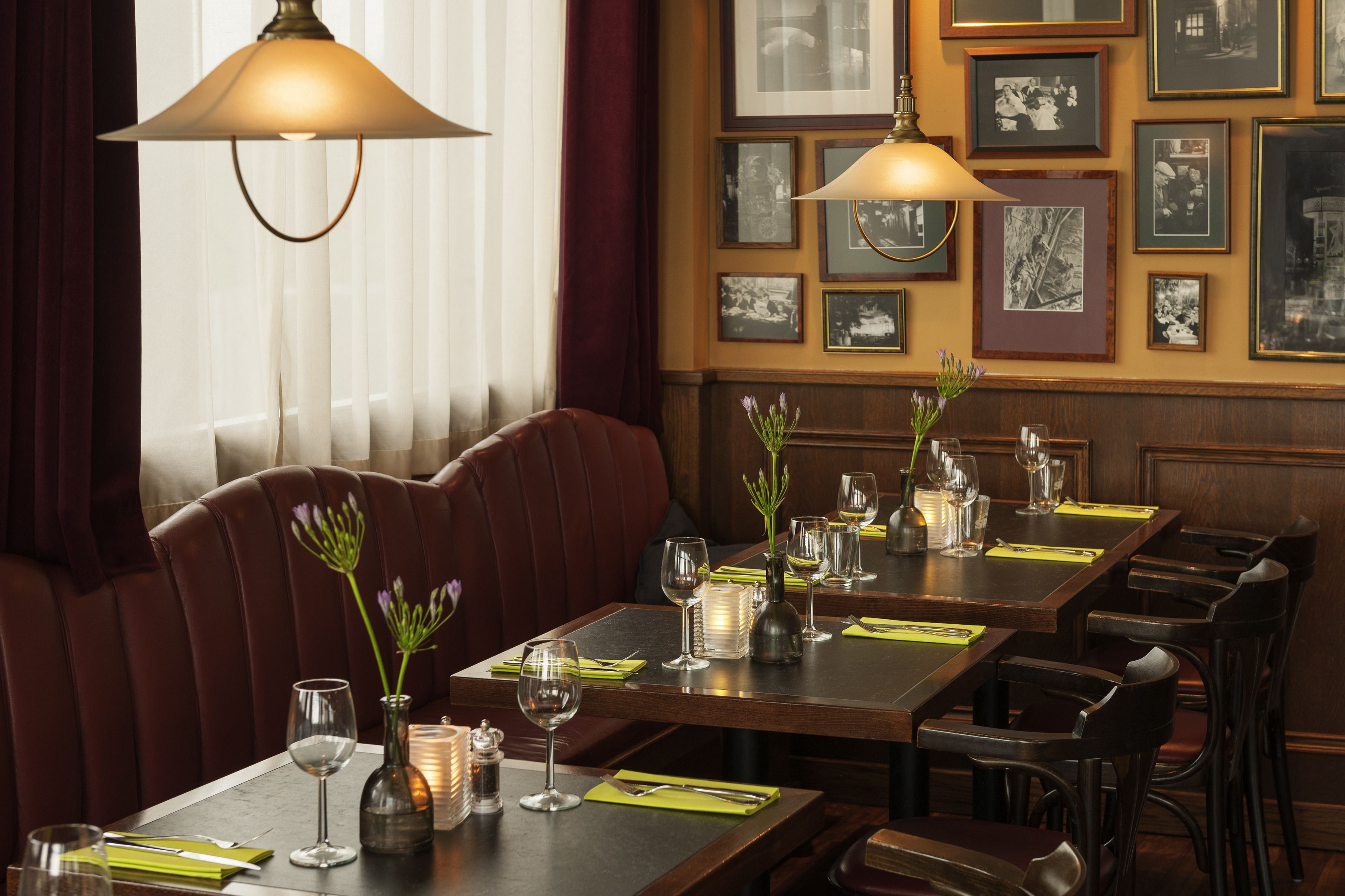 Un restaurante con mesas de madera, asientos de cuero color café y cuadros en las paredes.