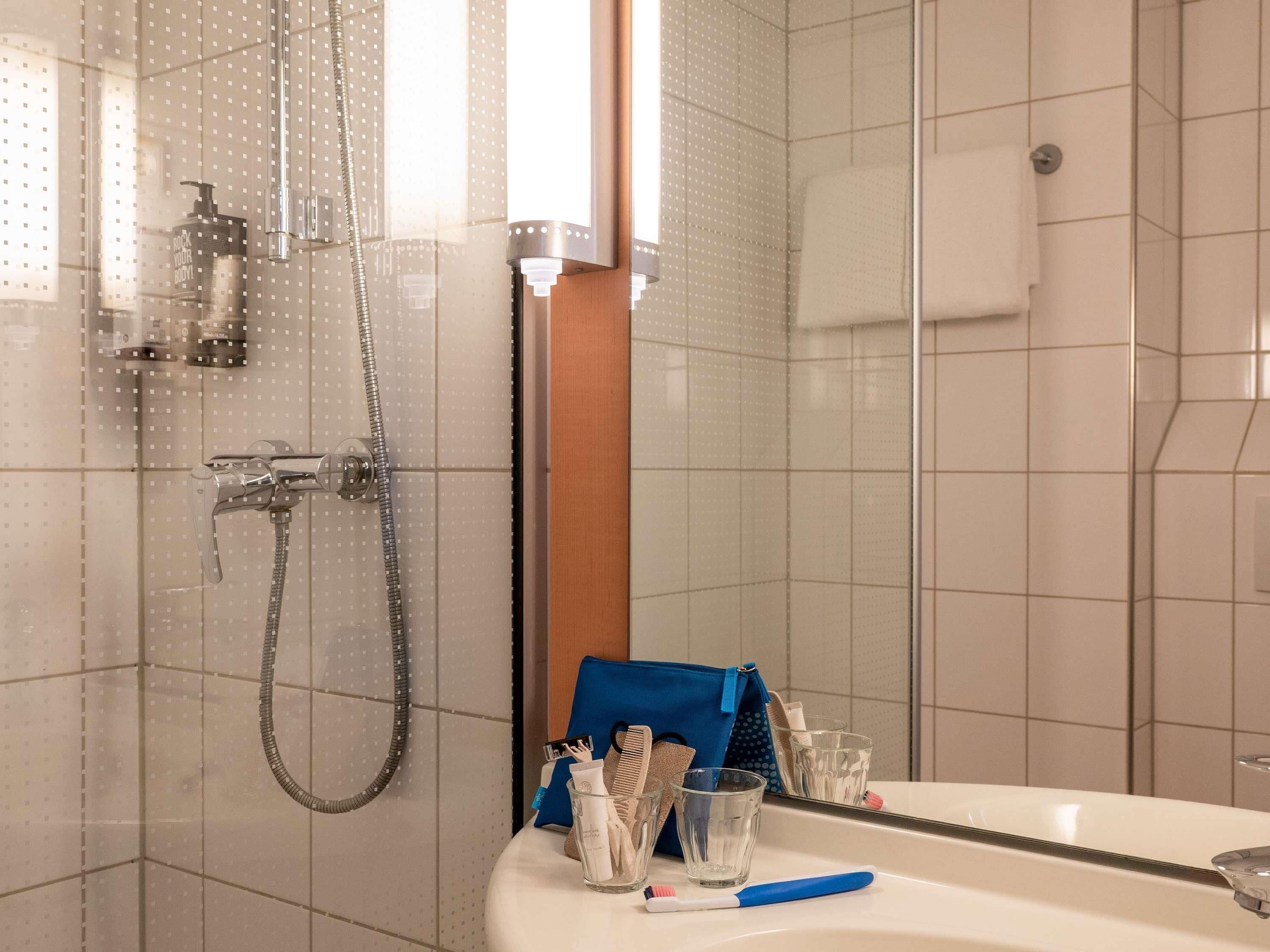 Une salle de bain avec une douche, un lavabo et un miroir.