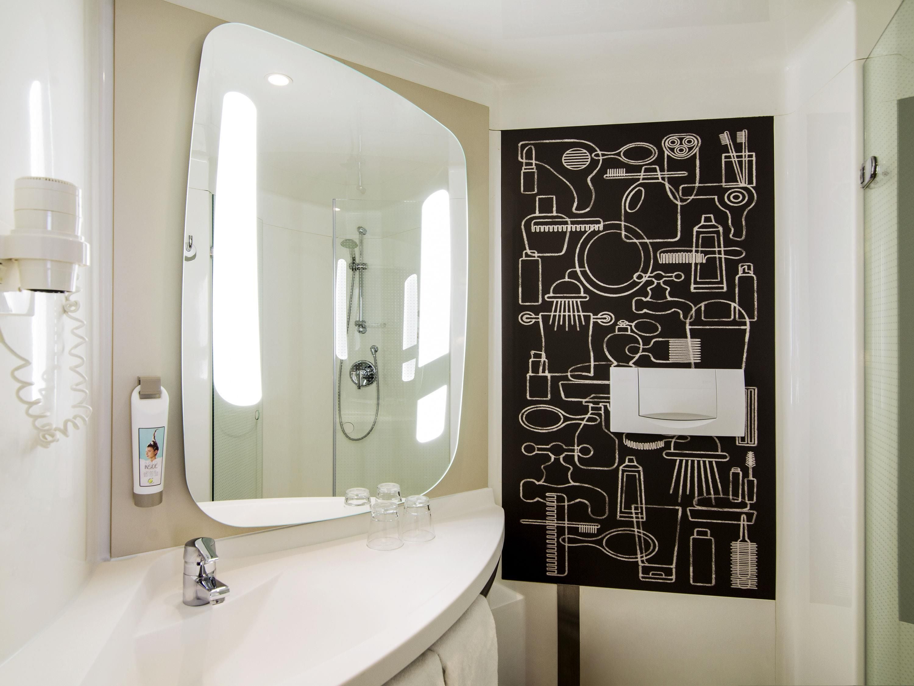 A bathroom with a large mirror, a shower, a sink, and a wall-mounted towel rack.