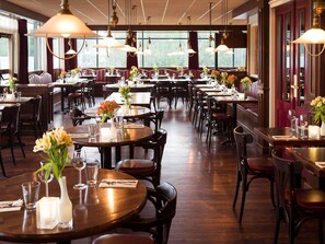 Un restaurante con varias mesas y cabinas, cada una dispuesta con vajilla y flores.