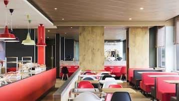 Un restaurante moderno con asientos rojos y blancos, una barra con exhibición de alimentos e iluminación colgante.