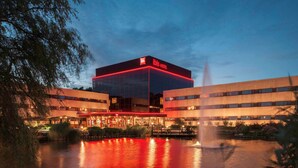 A modern hotel with a prominent glass facade and a red-lit entrance. - Hotel ibis Schiphol Amsterdam Airport (Badhoevedorp)