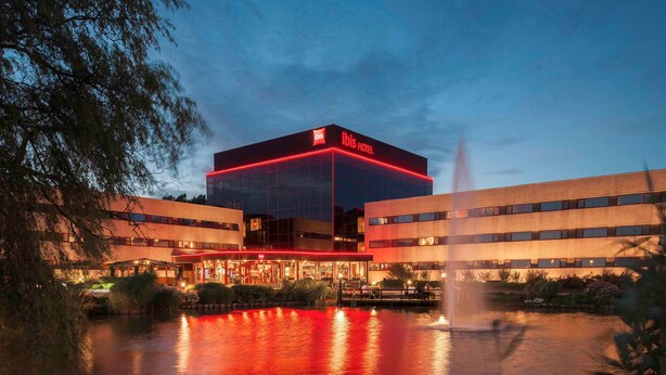 A modern hotel with a prominent glass facade and a red-lit entrance.