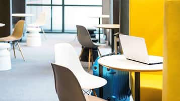 A modern lounge area with seating arrangements, a laptop on a table, and a suitcase.