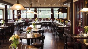 A restaurant with multiple tables and booths, each set with glasses, cutlery, and flowers.