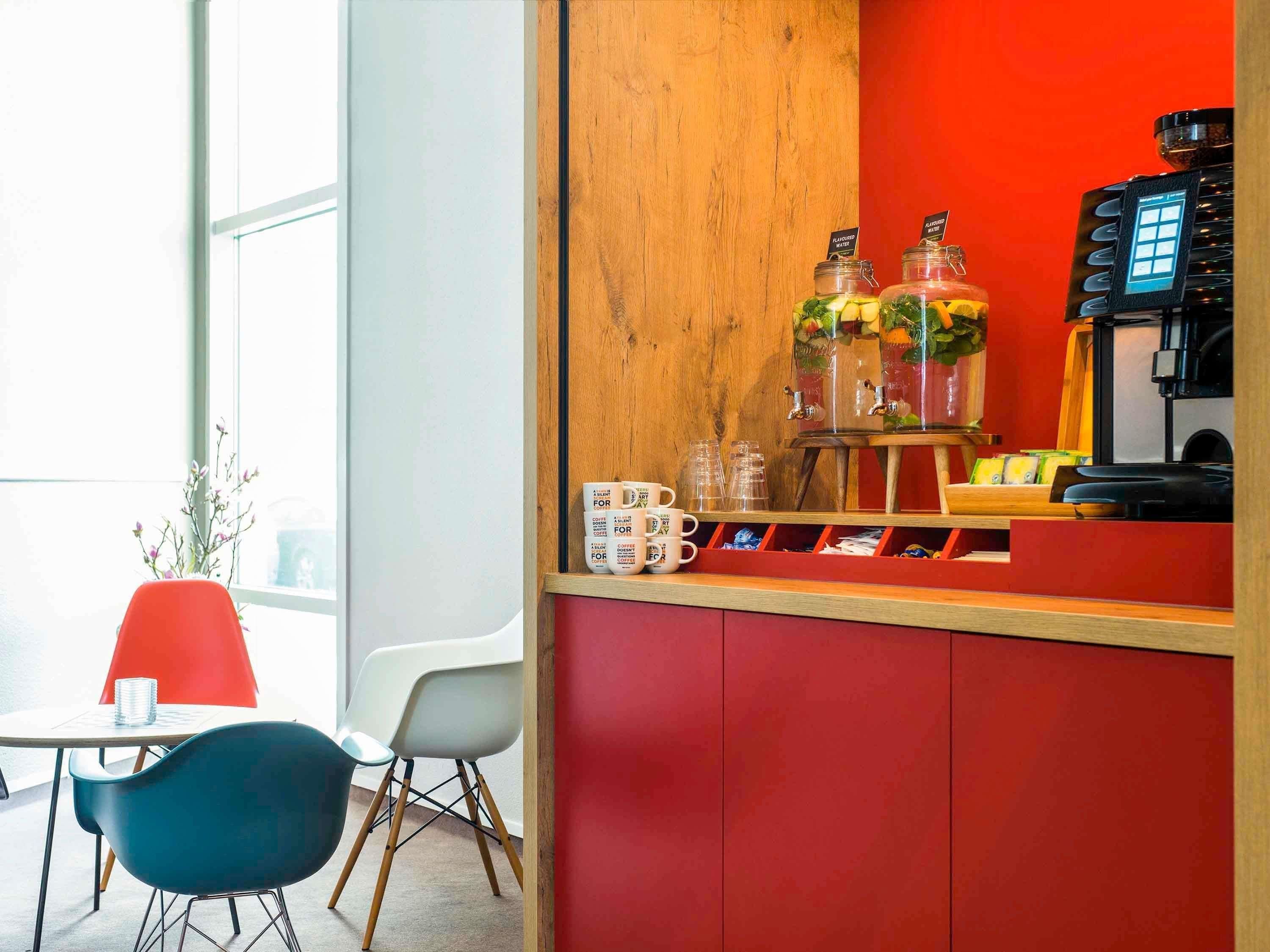 A coffee bar with a wooden counter, two glass dispensers, and a coffee machine.