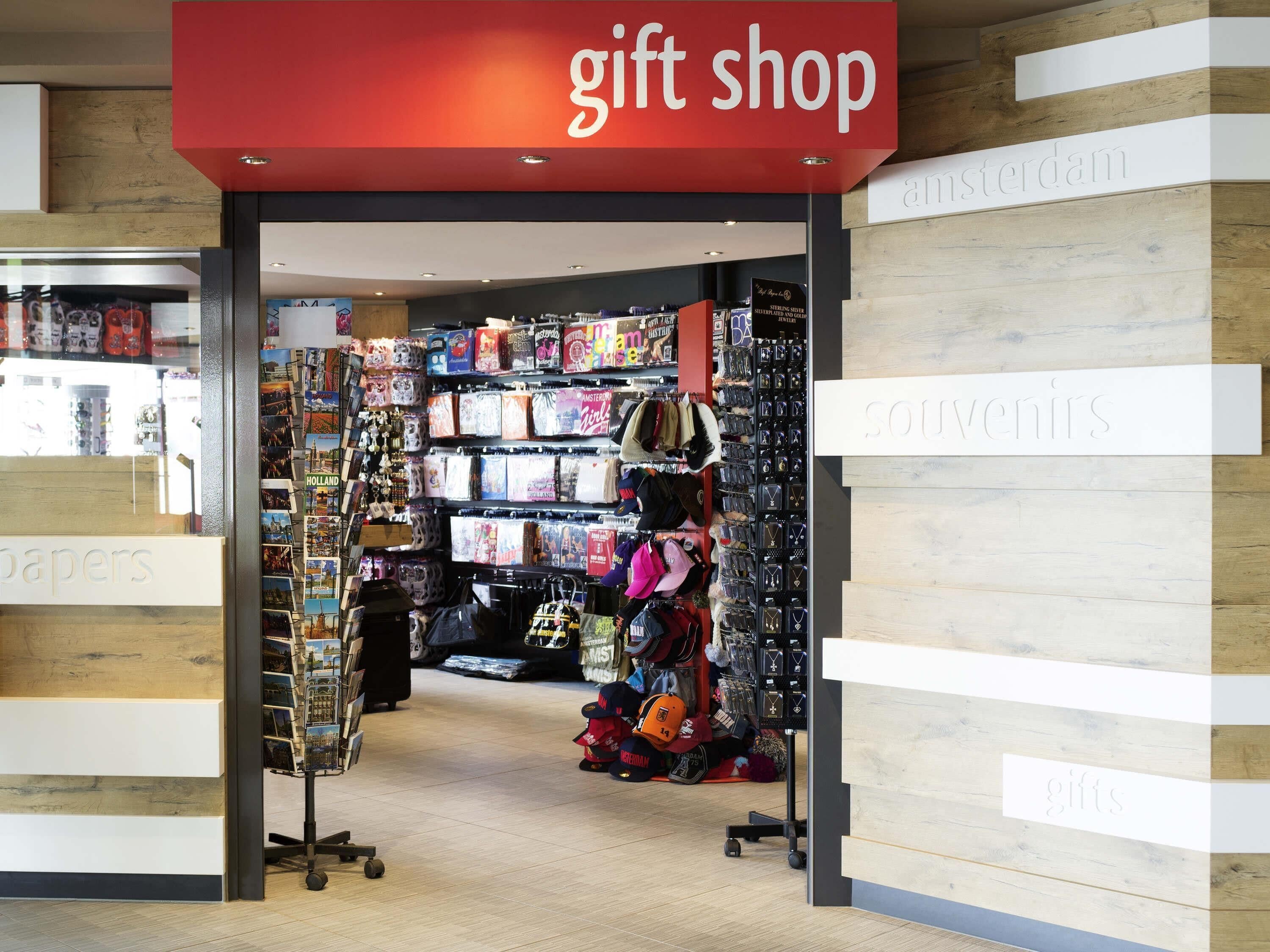 A gift shop with a red sign, shelves stocked with various items, and a display of hats and bags.