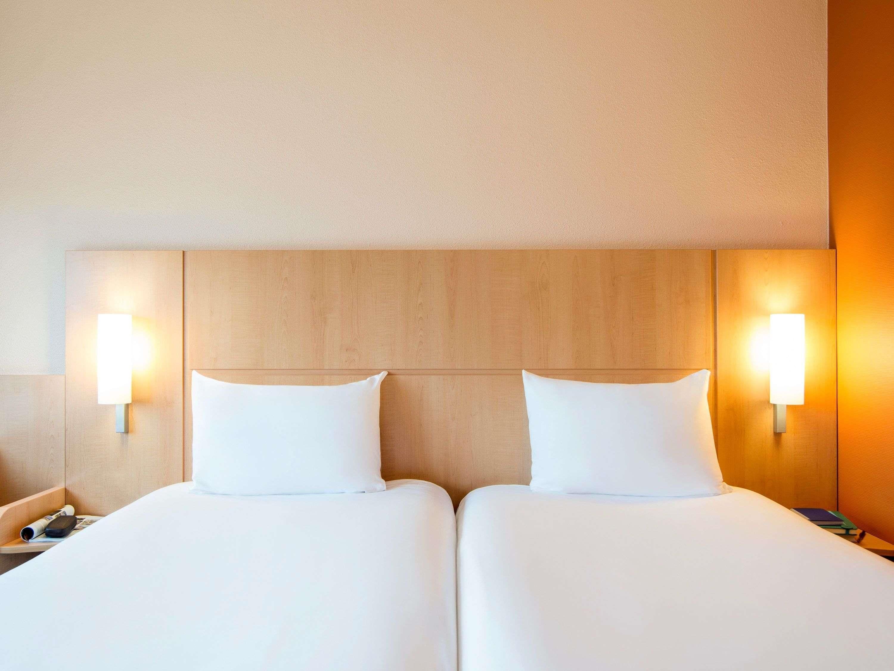 A double bed with two pillows and two wall-mounted light fixtures.