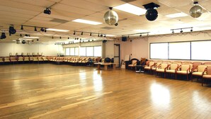 A large hall with rows of chairs, a stage, and a disco ball. - Metro Plaza Hotel (Los Angeles)